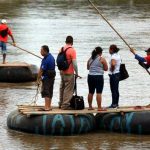 Un grupo de personas atraviesa en balsa el río Suchiate, cruzando la frontera entre Guatemala y México