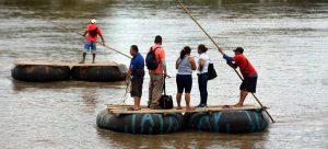 Un grupo de personas atraviesa en balsa el río Suchiate, cruzando la frontera entre Guatemala y México